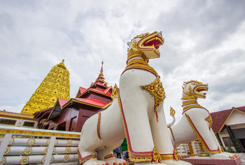 Golden Puttakaya chedi(pagoda) with two giant Chinthe at the entrance,Sangkhlaburi district,Kanchanaburi,Thailand.