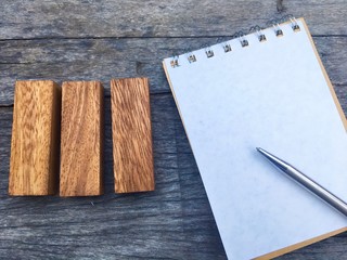 Three wooden block put beside notebook and pen for mathematics subject