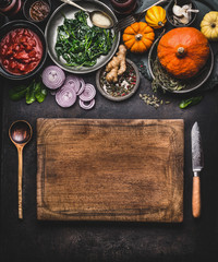 Pumpkin dish cooking. Food background with wooden cutting board, kitchen knife and spoon. Various vegetarian seasonal ingredients for tasty winter or autumn meal, top view. Clean healthy eating