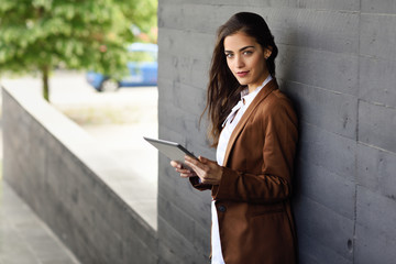 Businesswoman with tablet computer standing outside of an office building.