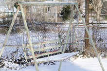 An Old Metal Two-person Swing Next To A Chain Link Fence The Morning After A Light Snowfall In Anniston, Alabama, USA
