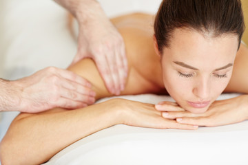 Young woman taking pleasure while having massage of her body