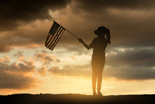 Young Girl Holding American Flag At Sunset. Silhouette Series.