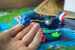 © Artem - Hand rolls the blue dice on the world map of the playing field handmade Board games with a pirate ship