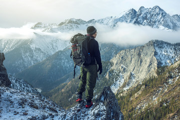 man hiker with backpack on top of the mountain back, looking at the snow slope. concept motivation a