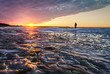 © ehrlif - Walking On The Edge. Silhouette of a single man walking on the edge of the open water of a frozen lake on the coast of Lake Huron in Michigan.