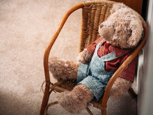 Soft Brown Teddy Bear Stuffed Animal Sitting In A Wicker Chair Dressed In A Checked Shirt And Dungarees