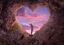 Young Woman In Heart Shape Cave Towards The Beautiful Sky