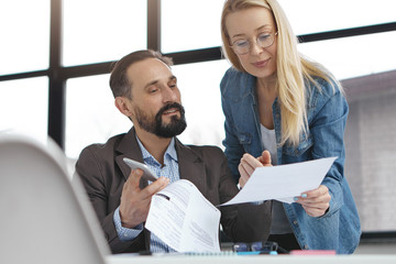 handsome bearded experienced man checks work of secretary who shows documents. account manager and h