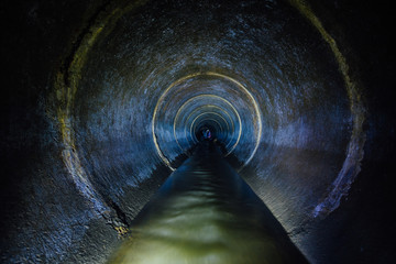 dark underground sewer round concrete tunnel. industrial wastewater and urban sewage flowing throw s