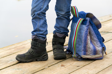  Kid boy legs and backpack on a wooden pier