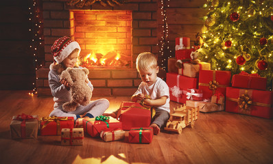 Wall Mural - happy children open christmas gifts at night at christmas tree