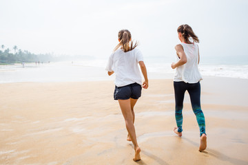 Wall Mural - two women is jogging the seashore on an overcast day