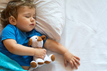 Cute Baby Boy Sleeping On The Bed At Home With Toy. Free Space