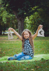 Little girl holding money at the hands. Concept. Outdoors.