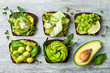 Fresh avocado toasts with different toppings. Healthy vegetarian breakfast with rye wholegrain sandwiches