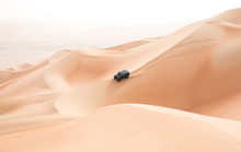 A Single Black Car Scaling Giant Sand Dunes In The Empty Quarter Desert. Abu Dhabi, UAE.