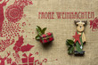 Frohe Weihnachten roter Schriftzug auf Jute, mit einem Päckchen und Holzelch Naturmaterialien