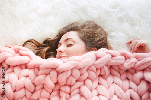 Fotografie, Obraz Young woman sleeping under warm peach color throw blanket