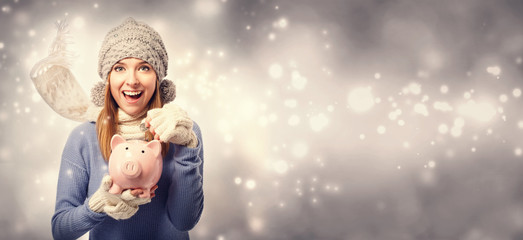 Wall Mural - Happy young woman depositing money into her pink piggy bank