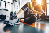 Fototapeta  - Asian woman exercising in the gym, Young woman workout in fitness for her healthy and office girl lifestyle. She is holding green apple.