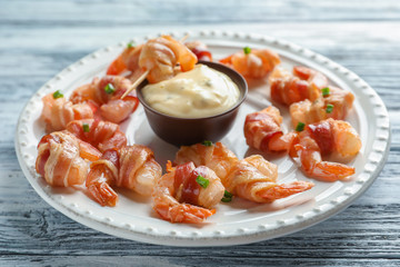 Canvas Print - Plate with bacon-wrapped shrimps and tasty sauce on wooden table