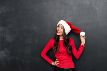 Poster - Happy brunette woman in red blouse and christmas hat