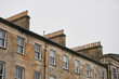 Rows of chimneys on a historic tenement building made of beige sandstone, typical to UK