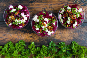 Wall Mural - Healthy beet salad with cheese, parsley, walnuts and Greek yogurt in small glass bowls on the rustic wooden table, top view.