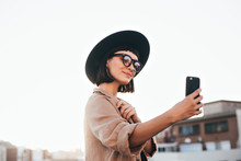 Cute And Pretty Fashion Trendy And Hipster Millennial Woman Or Girl Makes Selfie On Smartphone Camera To Share On Internet Social Media Channels, Self Absorbed New Generation Of Young People