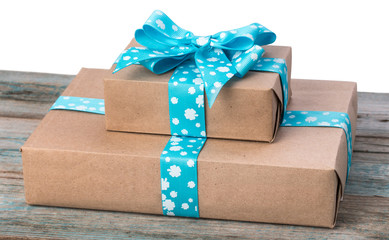 Pair of gift boxes wrapped in kraft paper with blue ribbon bow on old wood boards with vestiges of blue paint.