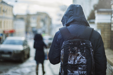 Hipster man in hood walking through city street