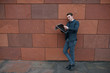 © Lalandrew - A young guy reads a newspaper against the background of an orange wall.