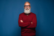 © stacestock - Portrait of handsome bearded man in fashion black glasses standing with arms folded isolated on a blue background in res sweeter. Happy bearded man look at the camera and smile