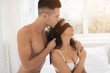 © VadimGuzhva - A young couple in their underwear sits on a white bed. The guy gently puts on the girl a black bandage over her eyes. Girl in anticipation