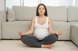 © Vadym Huzhva - Pregnant sport. A pregnant woman sits on a light floor at home. She does yoga exercises