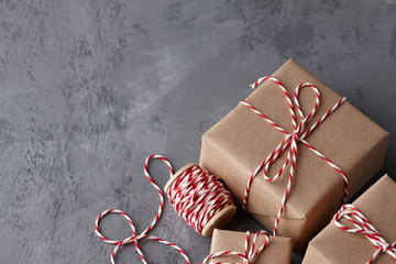 Wall Mural - Christmas gift or present boxes wrapped in kraft paper with striped baker's twine string on textured stone background, copy space