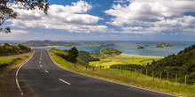 Inviting Road Through New Zealand Countryside With Blue Sea