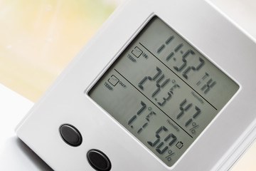 Wall Mural - Weather station device with weather conditions inside and outside. Background of a window with raindrops. Yellow background, golden autumn. Selective focus