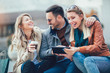 © Mediteraneo - Group of smiling friends with digital tablet outdoor
