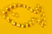 Omega-3 Fish Fat Oil Capsules Shaped In Fish On A Yellow