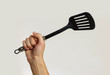 © OB production - Male hands holding a spatula for frying. Isolated on gray background. Closeup