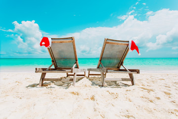 Wall Mural - Christmas on beach -chair lounges with Santa hats at sea