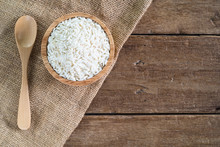 Raw White Sticky Rice In Wood Bowl With Wood Spoon On Gunny Sack Cloth On Wooden Table, Top View With Copy Space
