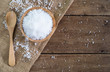 white sea salt in wood bowl with wood spoon on gunny sack cloth on brown wooden table, top view with copy space
