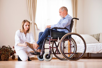 Wall Mural - Nurse and senior man in wheelchair during home visit.