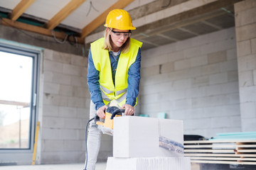 young woman worker with saw on the construction site.