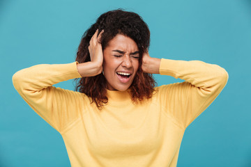 Wall Mural - Angry african woman in sweater screaming and covering her ears