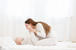 © Rithor - happy young mother kisses her little baby boy gently before bedtime. Mather's love and care. White clothes, light interior. Copy space