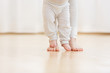 © Rithor - Cute baby boy learning to walk and make his first steps. mom is holding his hand. child's feet close up, copy space